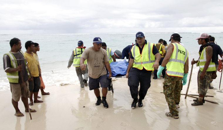 Image: Samoan police carry the body of a tsunami victim found in the water near Matavai on the southern coast of Western Samoa