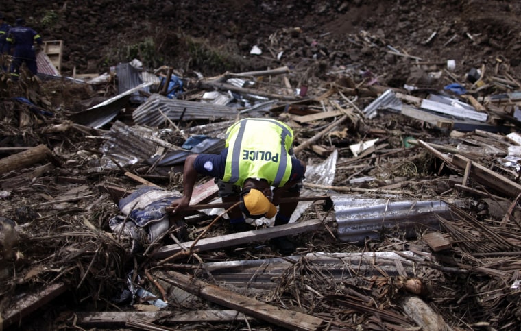 Image: Samoan policeman searches for tsunami victims on Samoa's southern coast