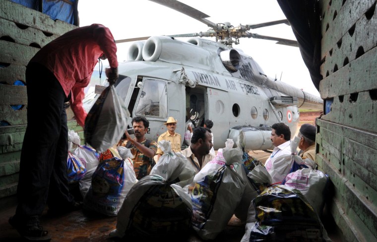 Image: Indian men load relief material inside an Indian Air Force Aircraft in Hubli to be distributed in Bijapur district