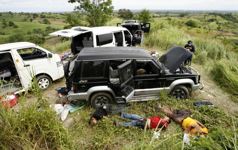 Image: Police investigator examines victims at the scene of a massacre on the outskirts of Ampatuan