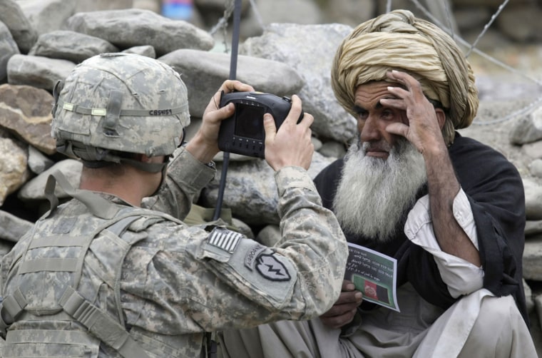 Image: U.S. Army soldier takes photos of the eyes of an Afghan man at a checkpoint near of the Forward Operating Base (FOB) Tillman