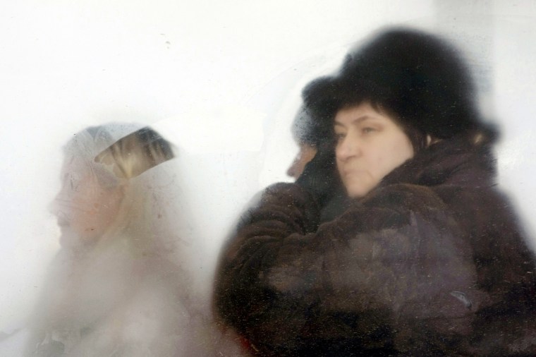 Image: Relatives of the victims of a fire sit in a bus as they wait to identify corpses at a local morgue in Perm