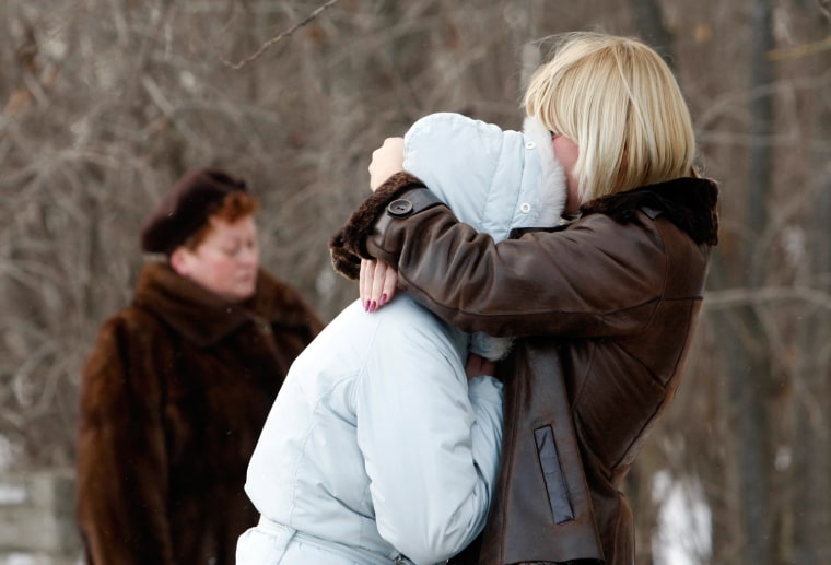 Image: Relatives of a victim of a fire embrace after taking part in a corpse identification procedure at a local morgue in Perm