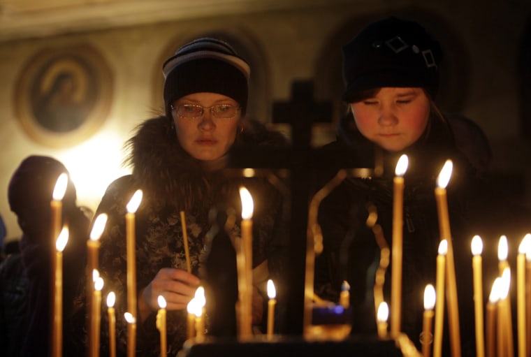 Image: People light candles during a commemorative service for victims of a fire at the Cathedral of Life-giving Trinity in Perm