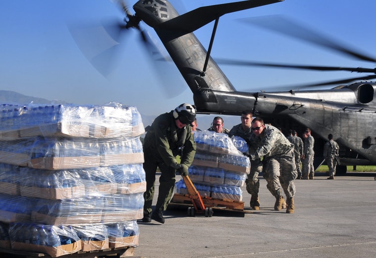 Image: Army soldiers help the crew of a U.S. Navy MH-53E Sea Dragon helicopter from the aircraft carrier USS Carl Vinson unload food and supplies at the airport in Port-au-Prince