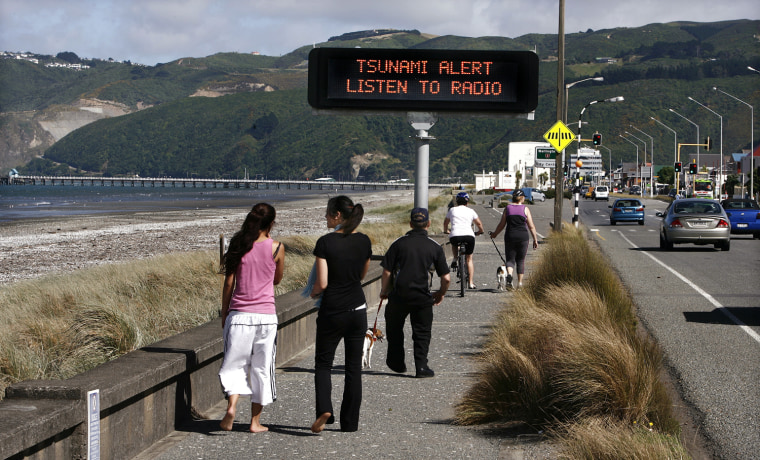Image: People walk past a Tsunami alert sign on the foreshore at Petone beach, near Wellington
