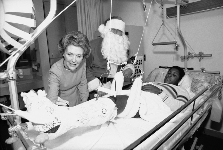 First lady Nancy Reagan autographs a leg cast worn by Tony Taylor, 17, a motorcycle accident victim, during a visit to Children's Hospital in Washington Friday, Dec. 18, 1981.     Accompanying Mrs. Reagan on her rounds was Santa Claus, better known as Willard Scott, popular weatherman on NBC's \"Today\" show. (AP Photo)