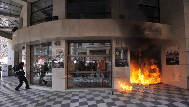 Image: A rioter sets fire to entrance of a hotel
