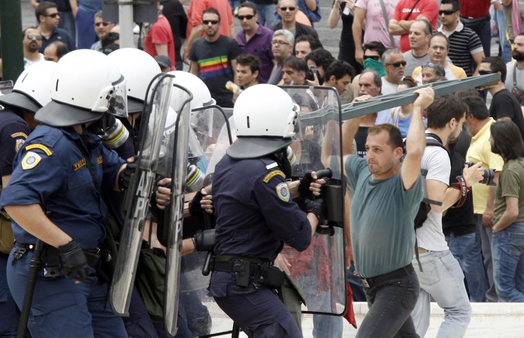Image: A demonstrator and riot police face off in Athens