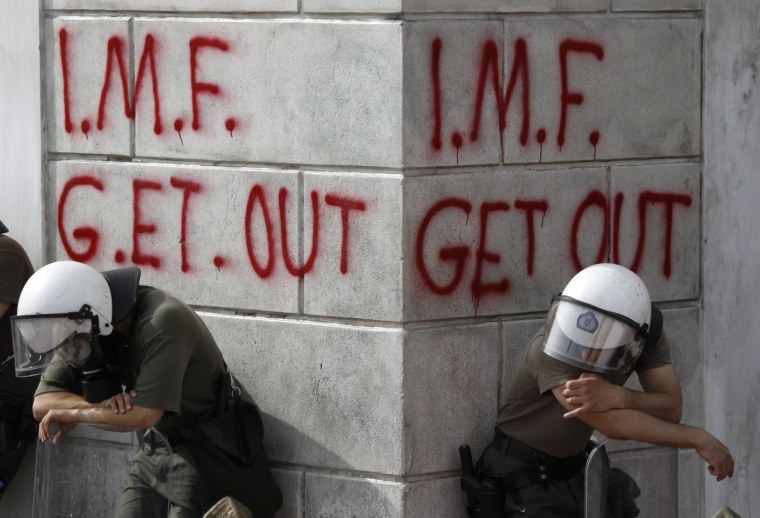 Image: Greek riot policemen rest in front of graffiti during violent demonstrations over austerity measures in Athens