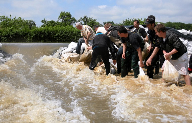 Image: Water gush through broken sand bags barrier set up by volunteers and emergency service workers against rising waters of the Sleza river caused by flash floods in Wroclaw