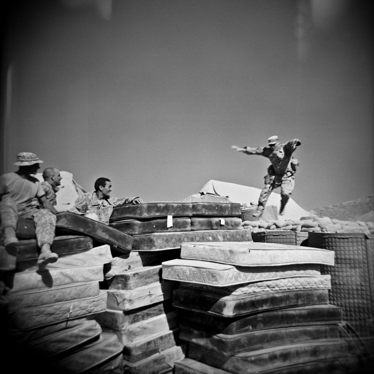 Left to right: US infantry soldiers (of Bravo Company, 1st Battalion, 32nd Infantry Regiment, 3rd Brigade, 10th Mountain Division), SGT John Virgadamo, SPC Matthew Ledford, and SPC Brian Lucey watch  SPC Adam Ramsey, right, jump onto a pile of mattresses at COP (Combat Operating Post) Charkh in the south of Logar Province, Afghanistan, Sept. 2009.