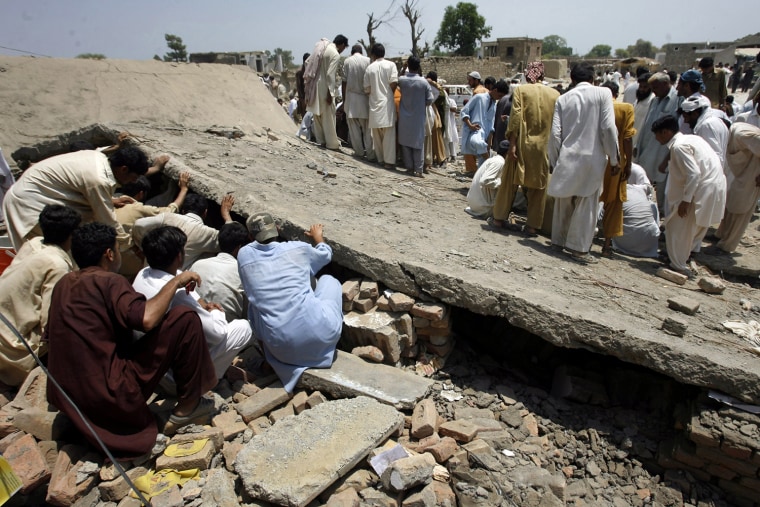 Image: Men search for survivors under the collapsed roof top of a building at the site of a suicide bomb blast in Pakistan's northwestern Mohmand region