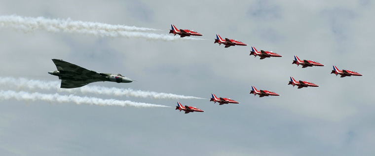 Image: The Royal Air Force Red Arrow display team and a Vulcan aircraft fly over the 2010 Farnborough International Airshow
