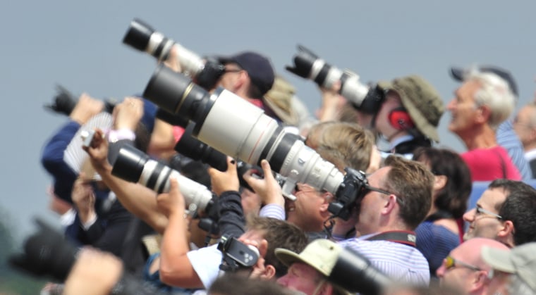 Image: Spectators and photographers are seen through a heat haze as they attend the Farnborough Airshow