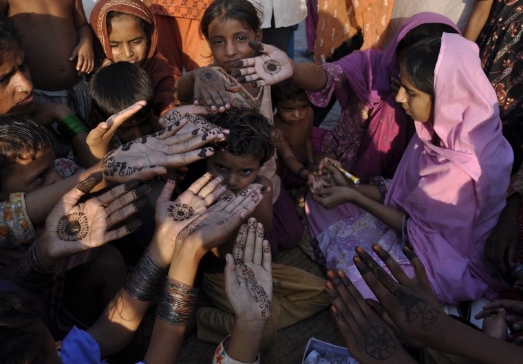 Image: Young flood victims have their hands decorated with henna by aid workers as Pakistani Muslims prepare to celebrate Eid Al-Fitr at their relief camp in Pakistan's Muzaffargarh district of Punjab province
