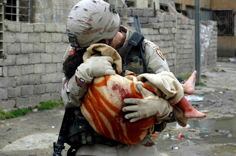 **REMOVES WITHHOLD ON  THE PHOTO AND ADDS PHOTOGRAPHER BYLINE** Picture released by the U.S. Army Tuesday, May 3, 2005 shows a U.S. Army soldier comforting a child fatally wounded in a car bomb blast in Mosul, 360 km (225 miles) northwest of Baghdad, Iraq, Monday, May 2, 2005. 15 Iraqis were wounded in the combined suicide bomb attack. (AP Photo/Michael Yon via U.S. Army)