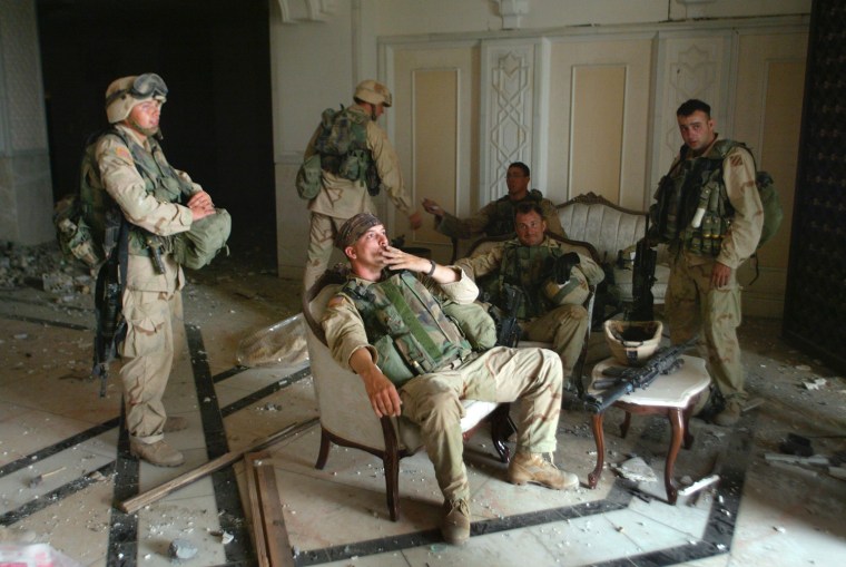U.S. Army Stf. Sgt. Chad Touchett, center, relaxes with comrades from A Company, 3rd Battalion, 7th Infantry Regiment,  following a search in one of Saddam Hussein's palaces damaged after a bombing, in Baghdad, Iraq, Monday, April 7, 2003.(AP Photo/John Moore)