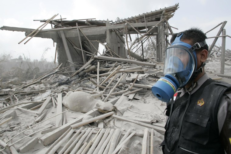 Image: A rescuer stands at a village hit by pyroclastic flows from Tuesday's eruption of Mount Merapi in Kinahrejo
