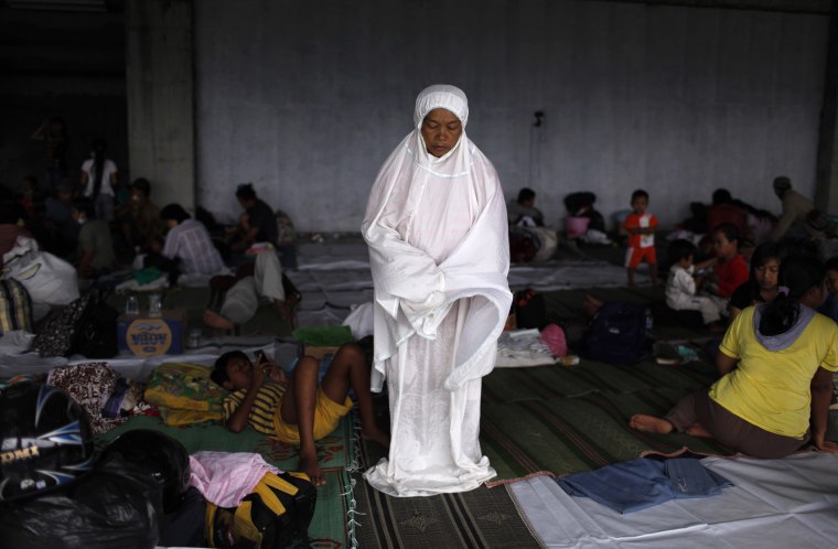 Image: A woman prays in a temporary shelter at Maguwoharjo Stadium in Yogyakarta