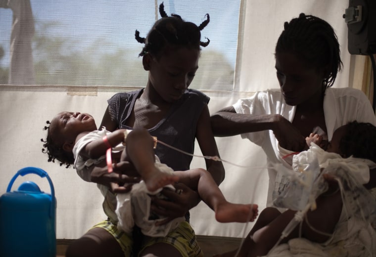 Image: Fifteen-month-old twins with cholera are held by their mother and sister as they receive IV's in the intake tent at a cholera clinic set up by Medecins sans Frontieres in Port-au-Prince