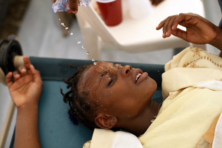 Image: Haitian girl with cholera symptoms is doused with water at an improvised clinic run by Doctor without Borders in Port-au-Prince