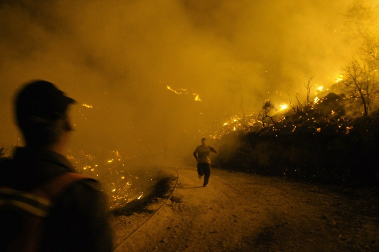 Image: An Israeli firefighter runs from raging