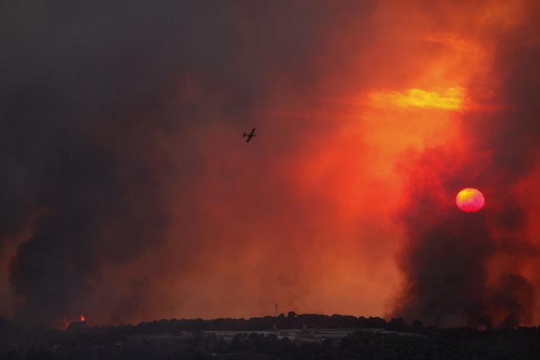 Image: A fire-fighting plane flies over a forest fire that broke out in the north of Israel