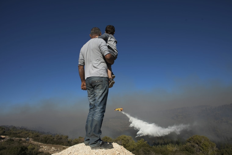 Image: Locals watch a  firefighting plane