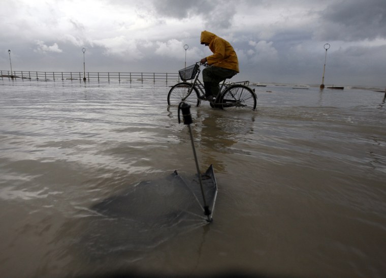 Image: A man rides his bicycle through a flooded street after a storm in Sidon port city in south Lebanon