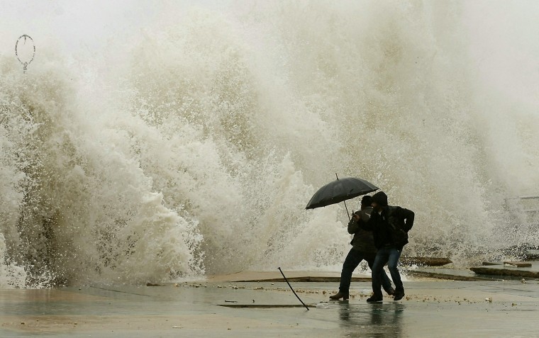 Image: Lebanese men react as waves crash into a
