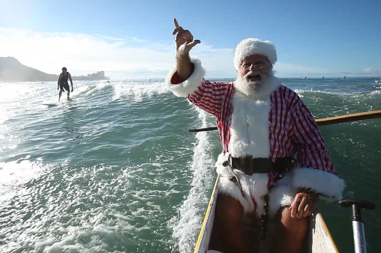 Image: Frame grab of Donald Boyce, dressed as Santa Claus, doing a \"shaka\" while riding in an outrigger canoe off Waikiki beach in Honolulu