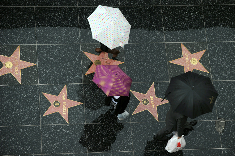 Image: Pedestrians walk under the rain on the s