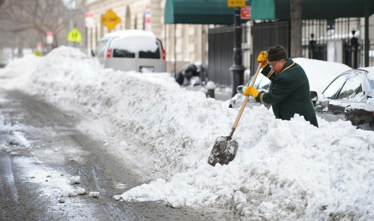 Image: A doorman shovels a path to the street o