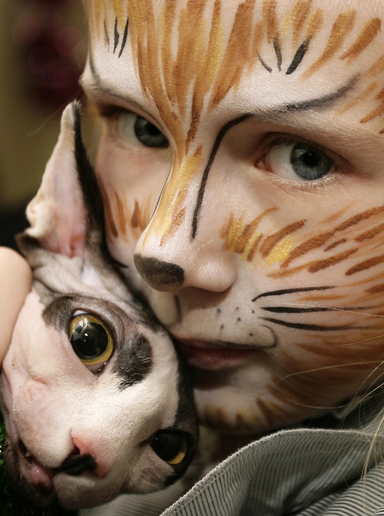 Image: A girl with cat makeup holds her 3-month-old Canadian Hairless during a cat exhibition dedicated to the New Year holiday in Rostov-on-Don