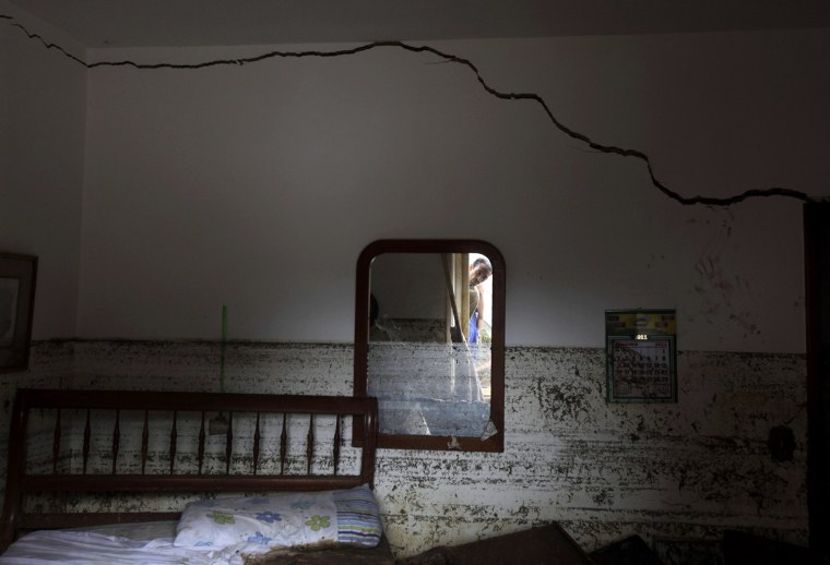 Image: A resident is reflected in a mirror at a destroyed house in Teresopolis