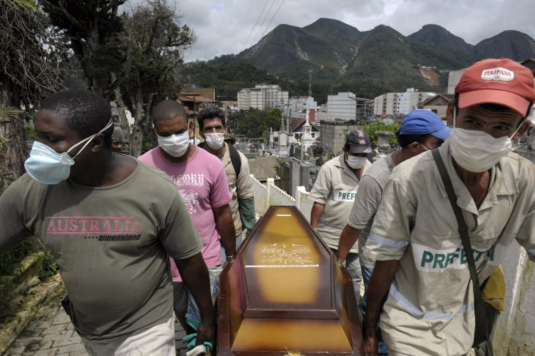 Image: Gravediggers carry the coffin of a landslide victim in Brazil