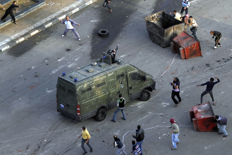 Image: Egyptian anti-government protesters attack a riot police car at the port city in Suez