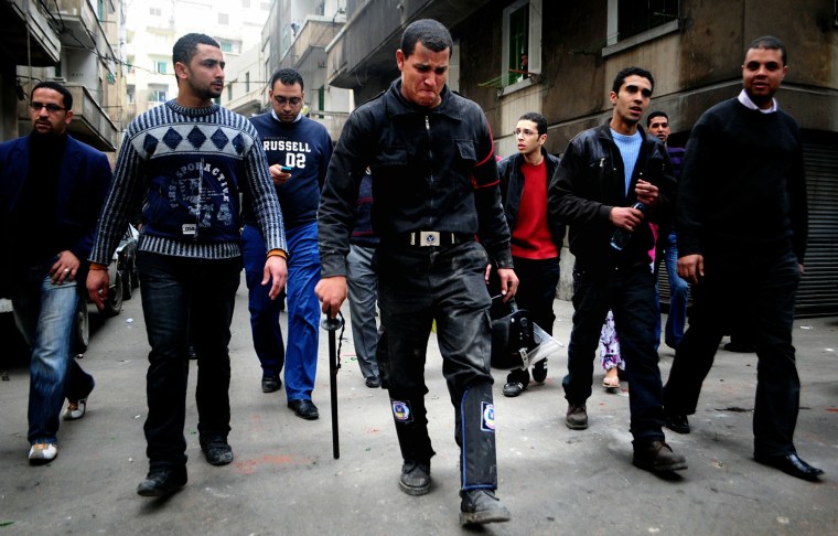 Image: Egyptian demonstrators escort a riot pol