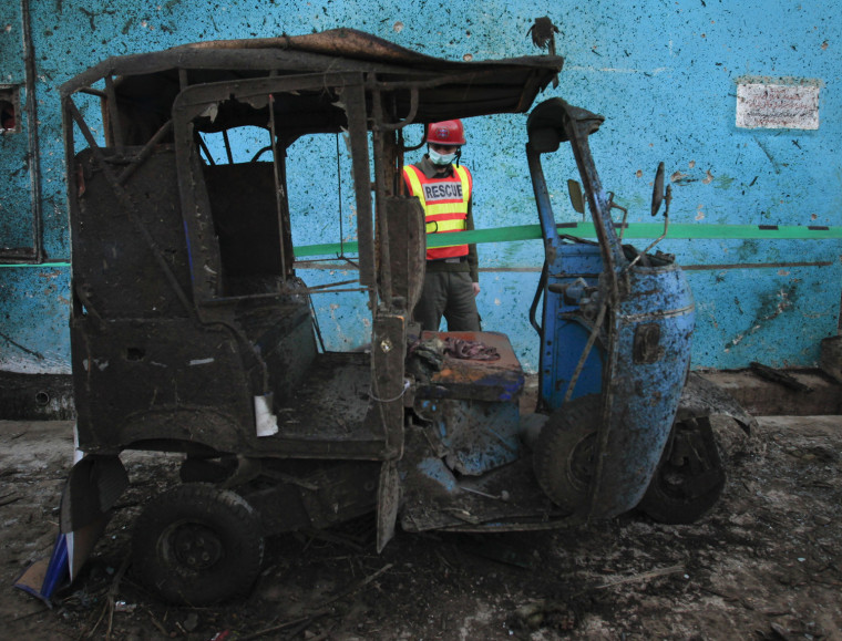 Image: A rescue worker looks at a rickshaw which was hit by a bomb attack outside a children's school in Peshawar