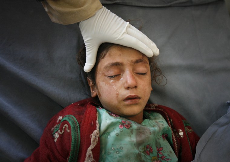 Image: A girl is treated by medics after suffering injuries from a bomb attack in Peshawar