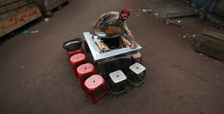 Image: A vendor cleans his stall as he prepares food at a market early morning in Karachi