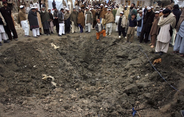 Image: Residents gather near a hole in the ground caused by a suicide bomb attack near a checkpoint in Hangu