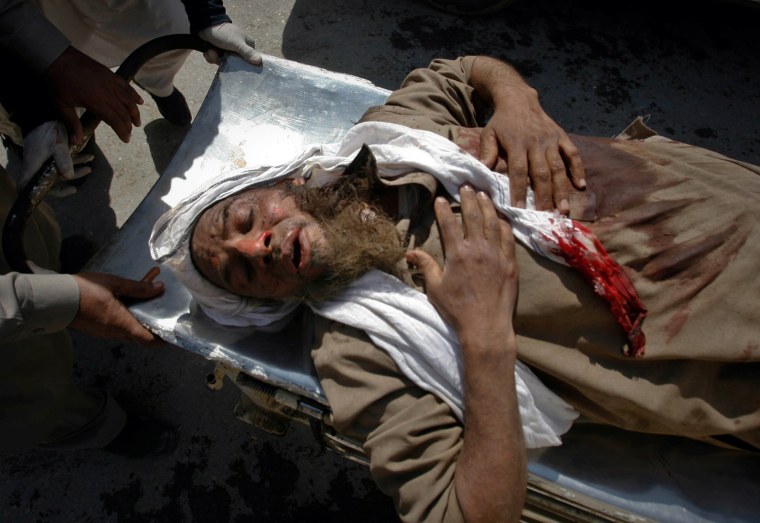 Image: Medics assist a man injured by a suicide bomb attack at a funeral procession on the outskirts of Peshawar, Pakistan