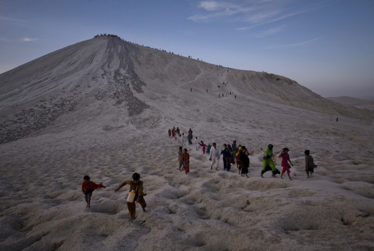 Image: Hindu devotees pay homage while moving from the crater of the Chandargup mud volcano to others nearby in Pakistan's Balochistan province