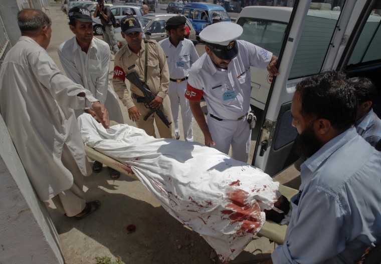 Image: Hospital workers and naval security officials move the body of a bomb blast victim to a hospital morgue in Karachi