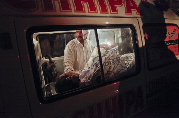 Image: A medic stands over a victim of a bomb blast after his body was brought by an ambulance to a local morgue in Karachi Pakistan