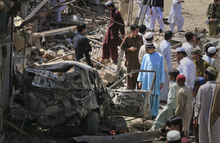 Image: Residents stand amidst the rubble near a police compound which was attacked by a suicide bomber in Hangu
