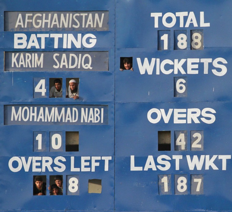 Image: Fans look through a score board as they watch the third match between Pakistan 'A' and Afghanistan in Faisalabad