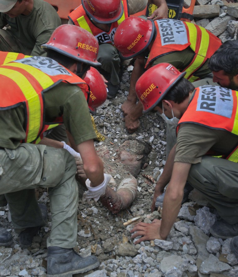 Image: Rescue workers retrieve the body of a victim from the rubble of a police station which was leveled by explosives in Peshawar
